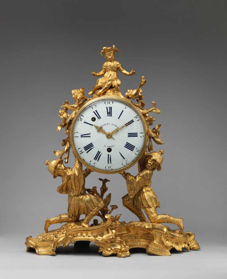 Antique French clock of about 1745, a gilt-bronze mantel clock with a scrolling case, small Chinese figures and a white enamel dial, shown against a gray backdrop