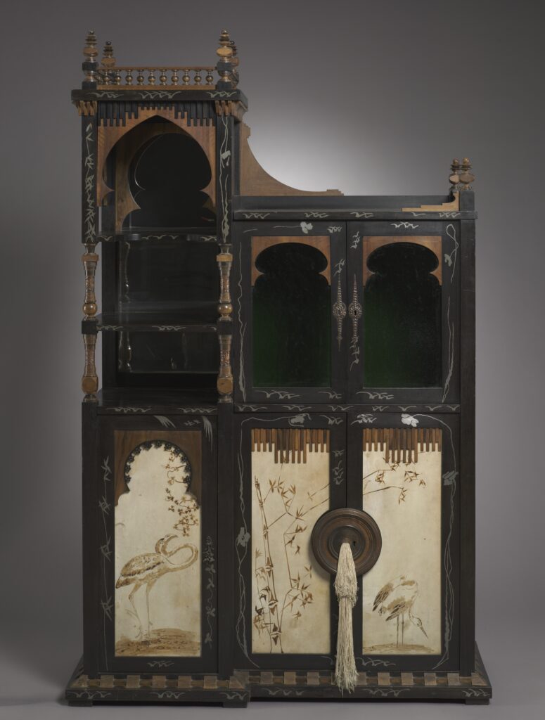 Tall asymmetrical dark cabinet with white-metal inlay, pointed-arch niches, glass doors and painted parchment panels showing birds and bamboo