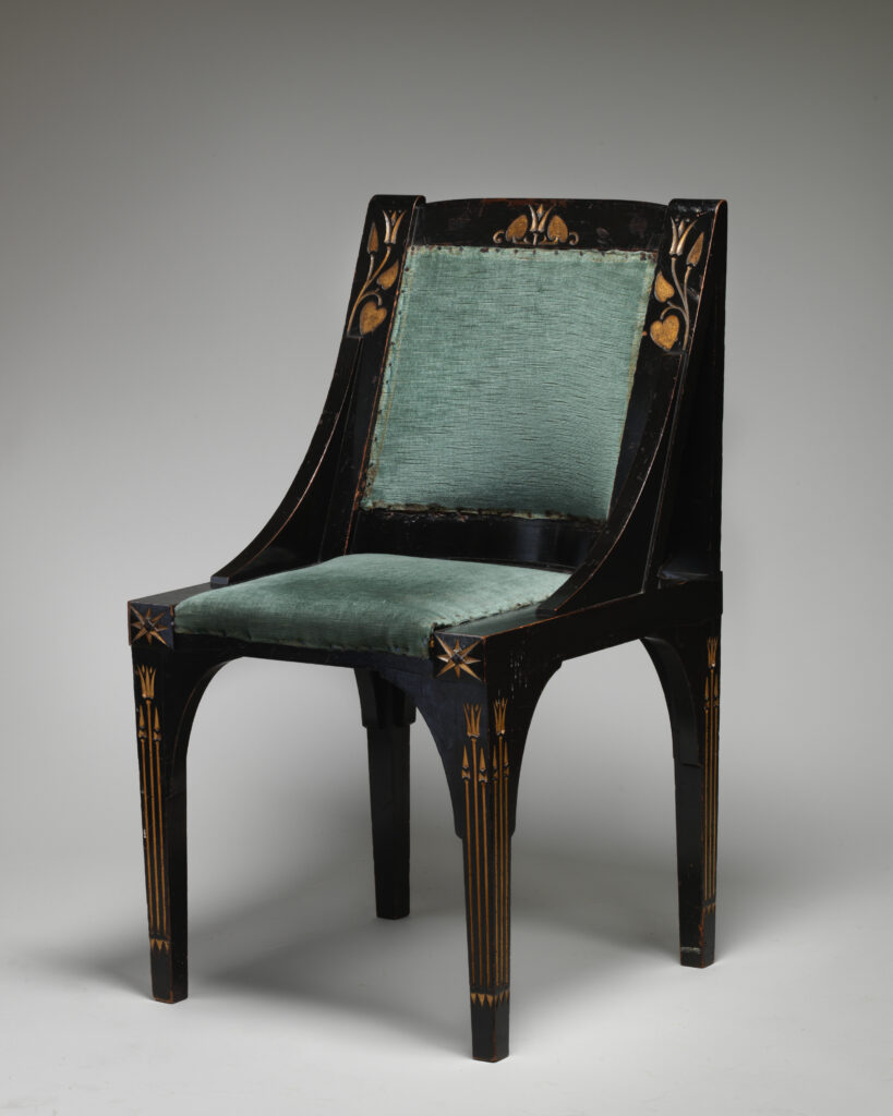 Black chair with a sloping padded back and seat in green plush, straight legs and fine gilt flower and line decoration on the legs and back, on a gray ground