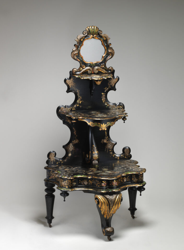 Black lacquered three-tier stand with scrolled shelf outlines, gilt and mother-of-pearl decoration, a small mirror in a gilded scrolling frame at the top and turned legs