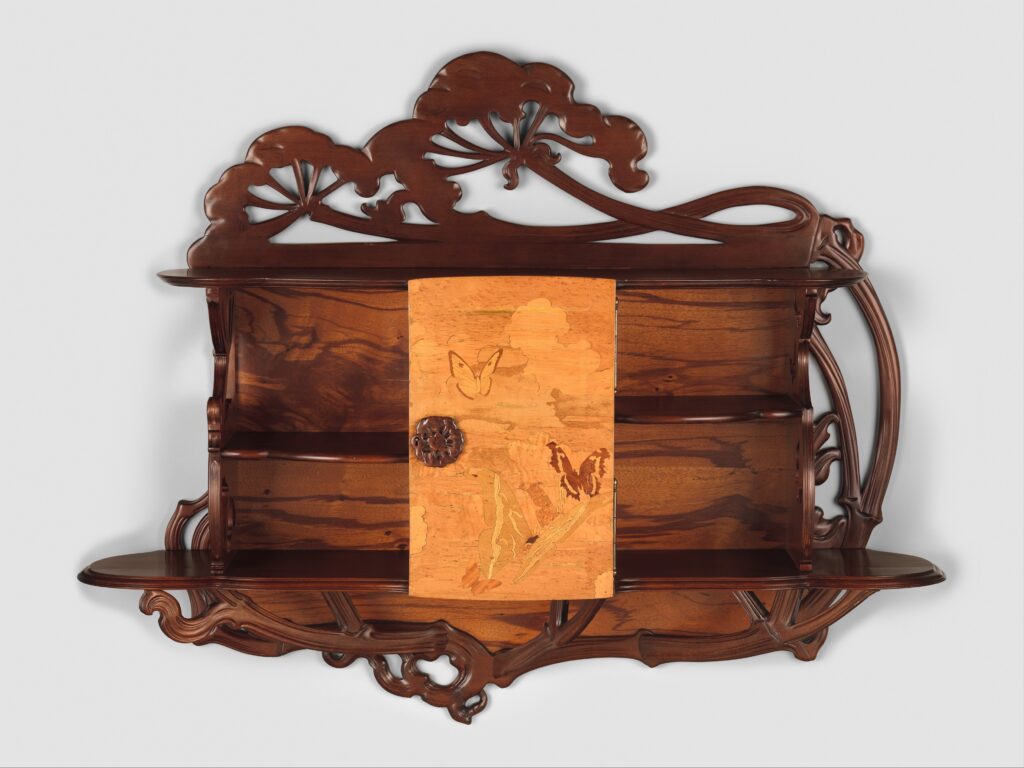 Dark wood cabinet with sinuous, plant-like carved outlines and an inlaid door panel showing butterflies and cow parsley