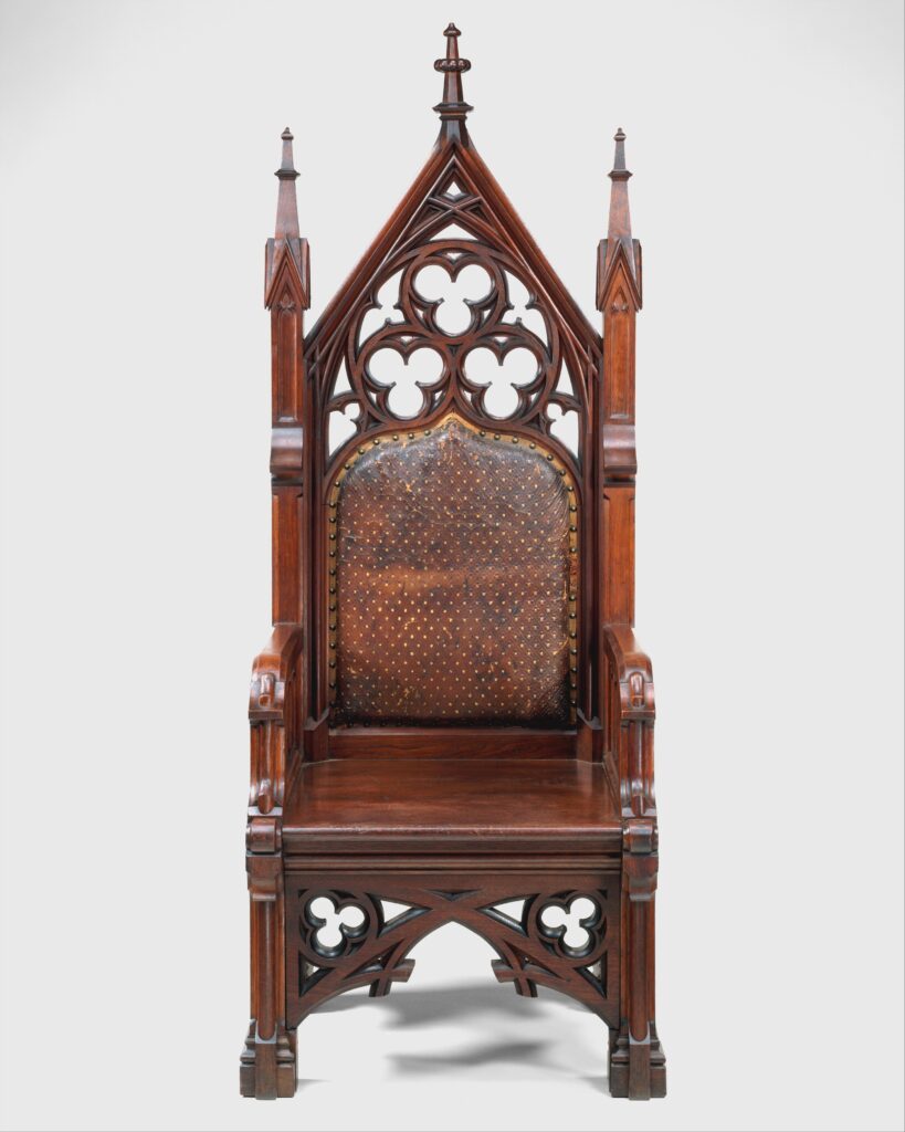 Tall walnut armchair with a pointed-arch back pierced with trefoil tracery, small pinnacles at the top and sides, and a studded leather panel