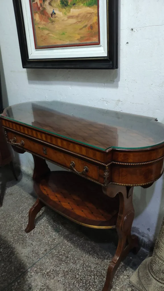 Oval console with parquetry top under glass and a shelf below