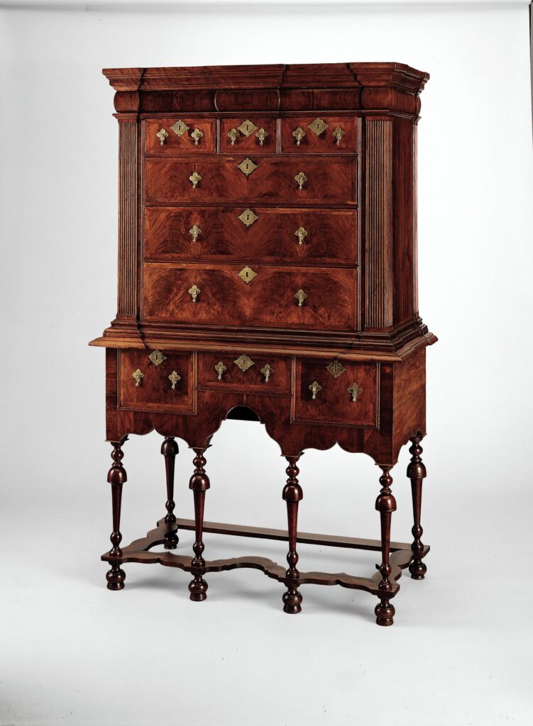 American high chest of drawers of 1715-30 in black walnut: a case of drawers with brass pulls standing on a stand of turned legs joined by a shaped stretcher
