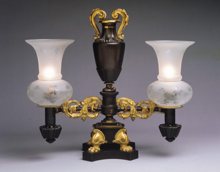 Antique Argand lamp in gilt and dark bronze, with a vase-shaped reservoir, two curved arms carrying frosted glass shades, on a pedestal base with paw feet