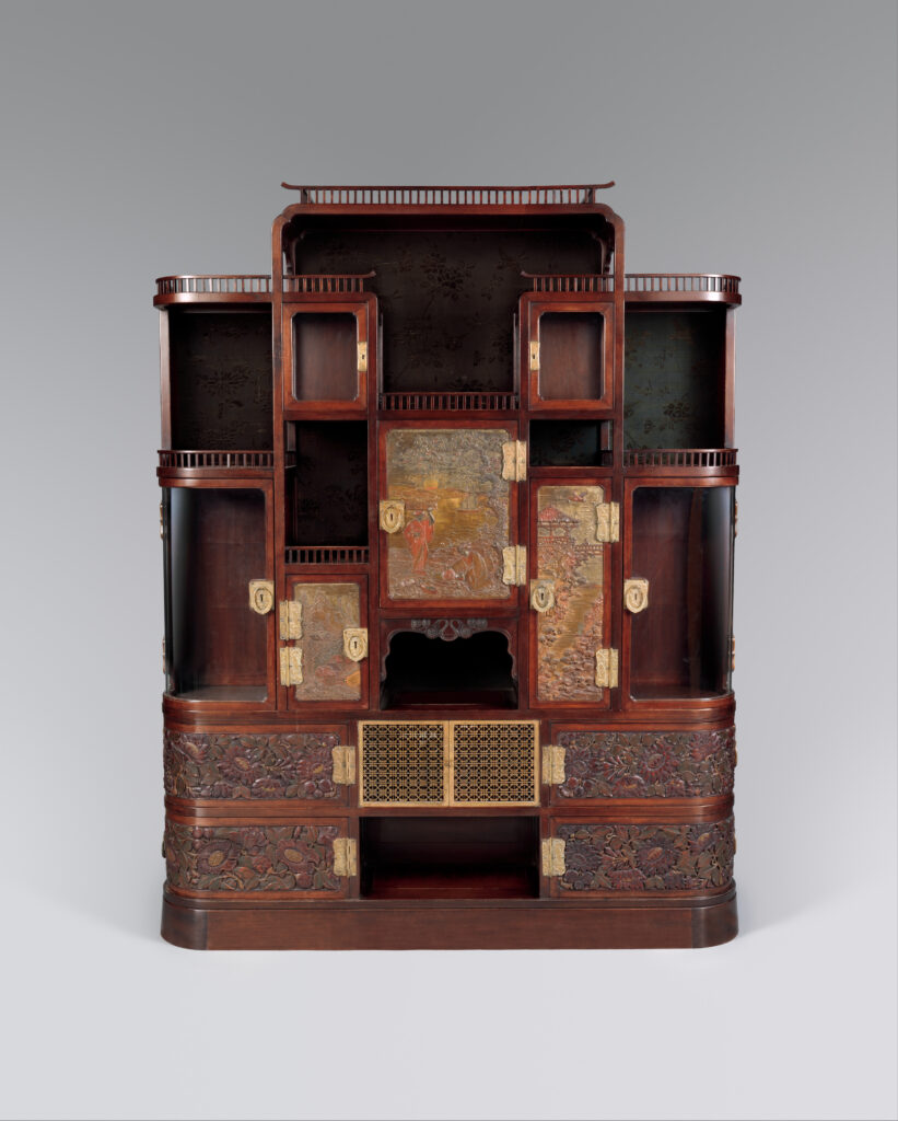 Dark wooden cabinet with asymmetrical stepped shelves and small open compartments above, gold and red carved panels in the lower doors and a pierced brass grille at the centre