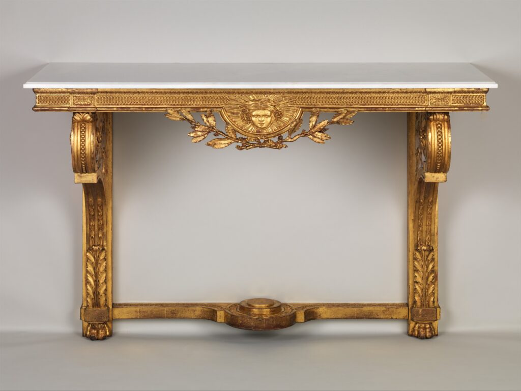 Gilded console table with a straight white marble top, a frieze with a central carved mask and swags, two scrolled supports and a low stretcher