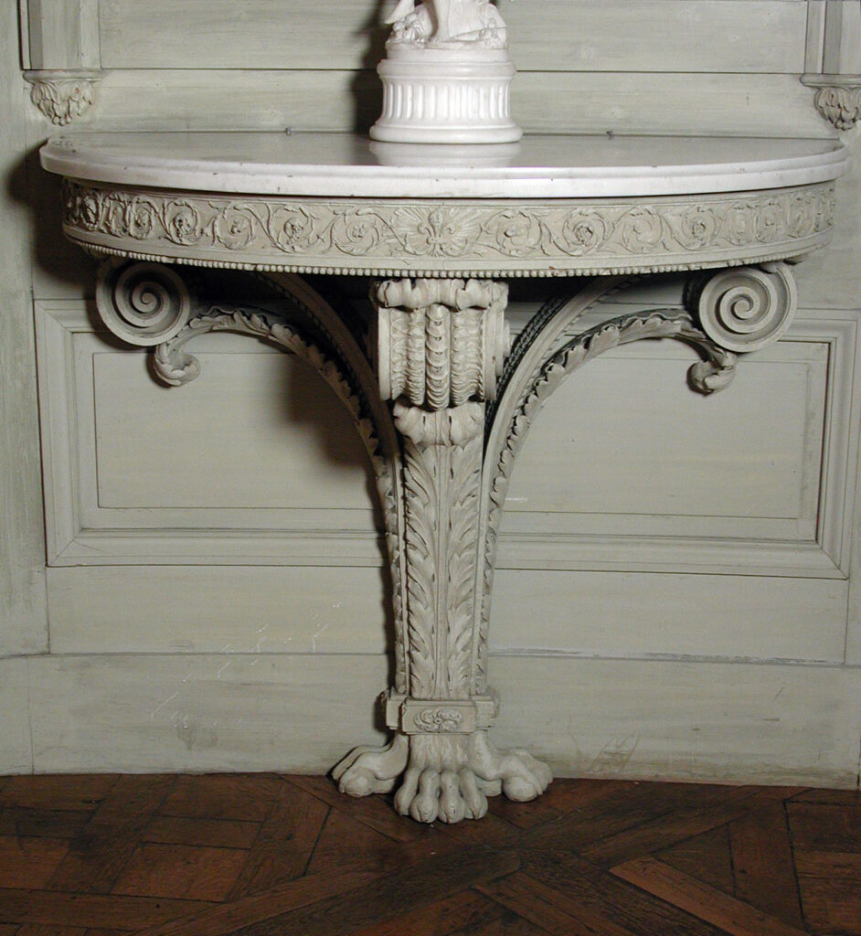 Grey-painted half-round console table with a white marble top, a frieze carved with a band of beads and foliage and a scrolled support ending in a clawed foot, set against a panelled wall