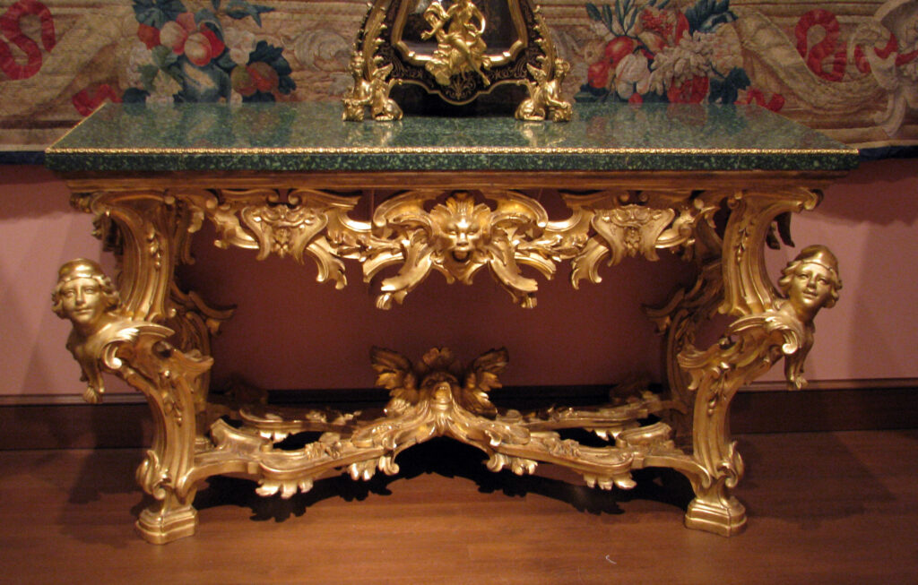 Rococo style vs Baroque furniture: the Baroque side, a Rome console table with scrolled legs carved with female busts, a gilded base and a green porphyry top
