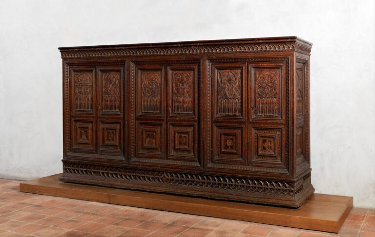 What is a credenza? An Italian example of 1440-50, a long walnut cabinet on a plinth, its front divided into three pairs of doors carved with rose-window forms above rows of pointed lancets and square panels of geometric inlay