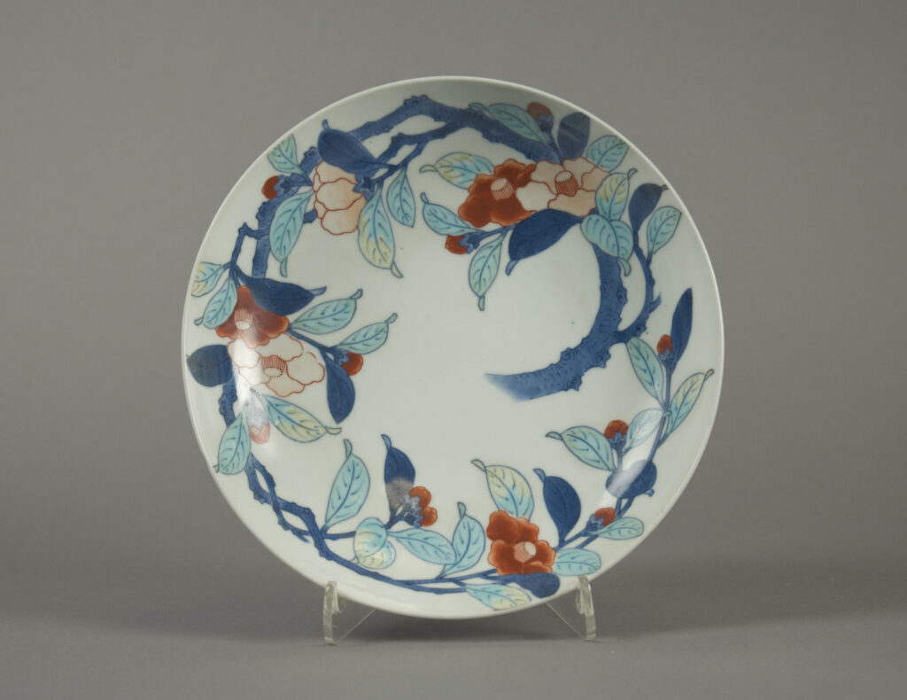 White dish painted with a camellia branch in blue, with red and orange flowers
