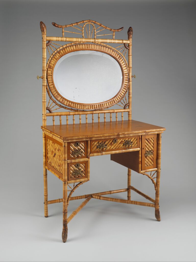 Bamboo dressing table with a pagoda-style cresting, an oval mirror and a central bank of drawers, photographed against a grey studio ground