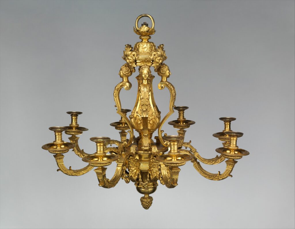 Heavy gilt-bronze chandelier with eight scrolling arms, a pillar of female busts and satyr masks, and a cluster of leaves at the base