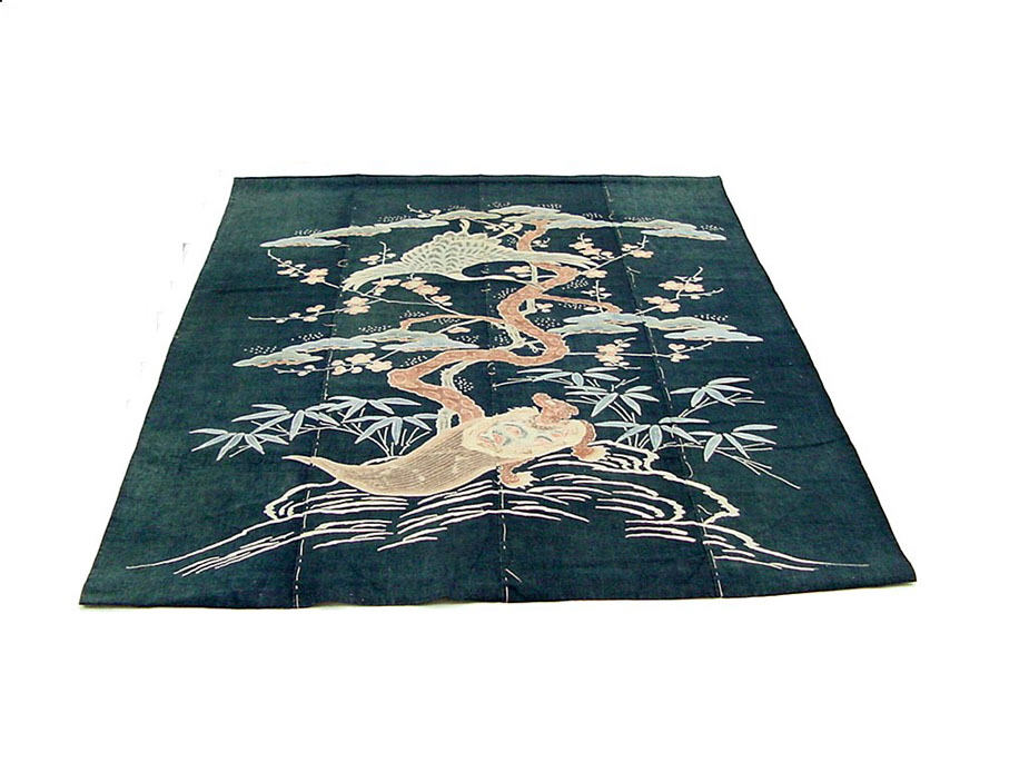 Dark indigo cotton futon cover laid flat and photographed at an angle, with a pale resist-dyed design of pine, bamboo and a bird