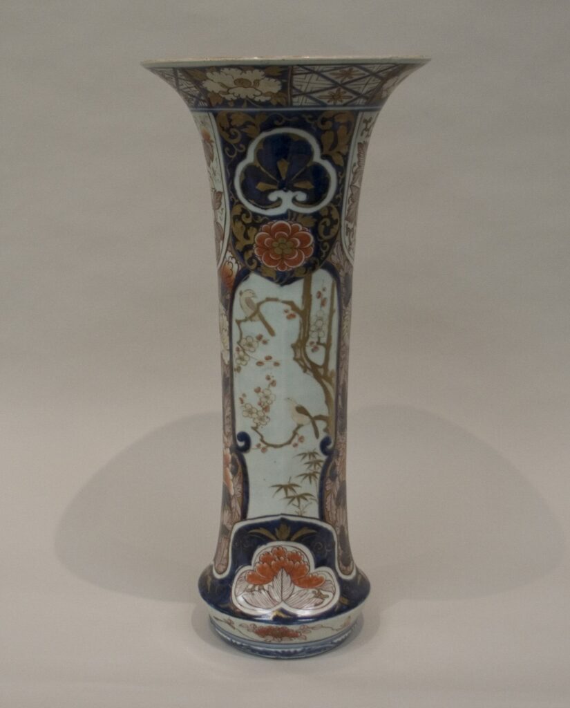 Tall slender Imari vase with a flared mouth, painted in blue, iron red and gold with panels of birds and flowers