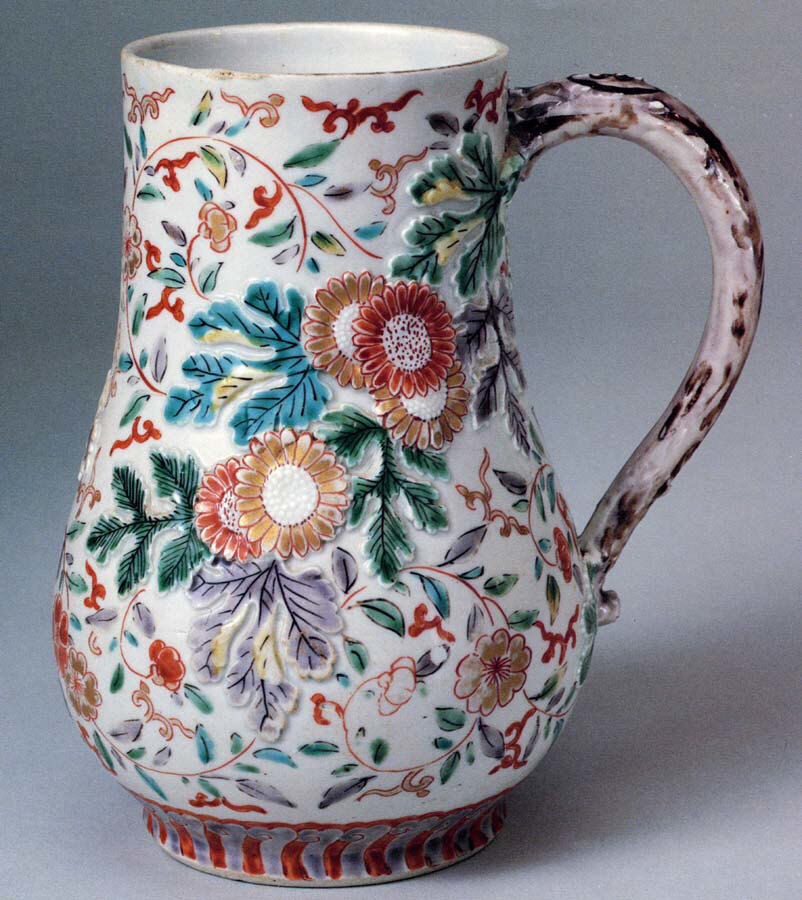 Pear-shaped Imari tankard with a looped handle, painted all over with large flowers and leaves in red, green and blue