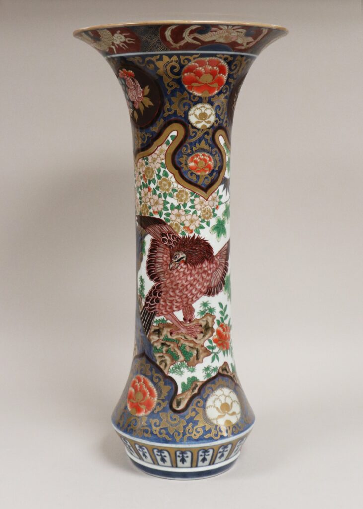 Very tall Imari beaker vase with a flaring mouth, painted with a large bird among flowers and bands of red, green and blue