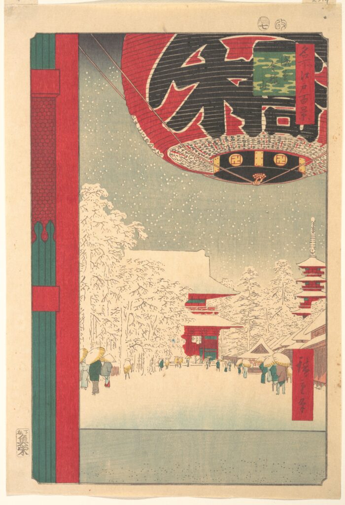 Colour woodblock print of a snow-covered temple precinct seen past a huge red paper lantern with black lettering that fills the top of the frame, with tiny figures walking below