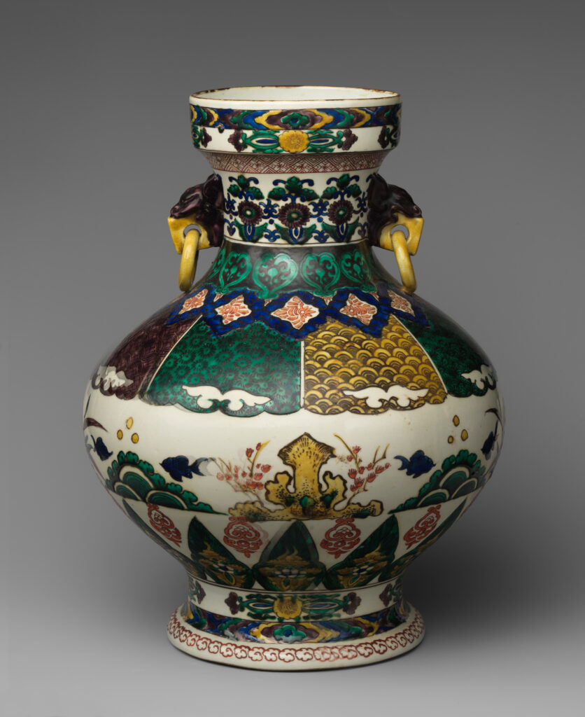 Two-handled porcelain vase with a white body painted in green, purple and blue panels, with yellow ring handles on dark lion-head mounts