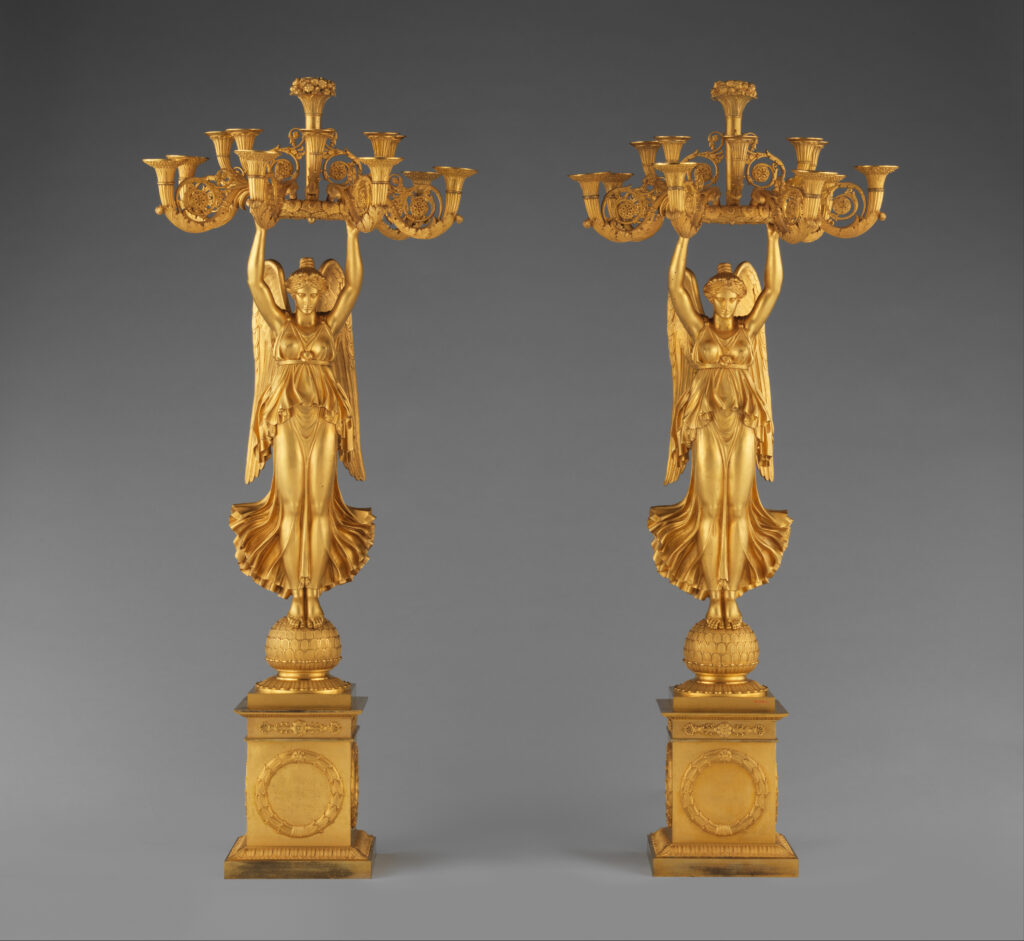 Pair of gilt-bronze candelabra, each a winged figure of Victory with raised arms holding a ring of candle sockets, on a square base
