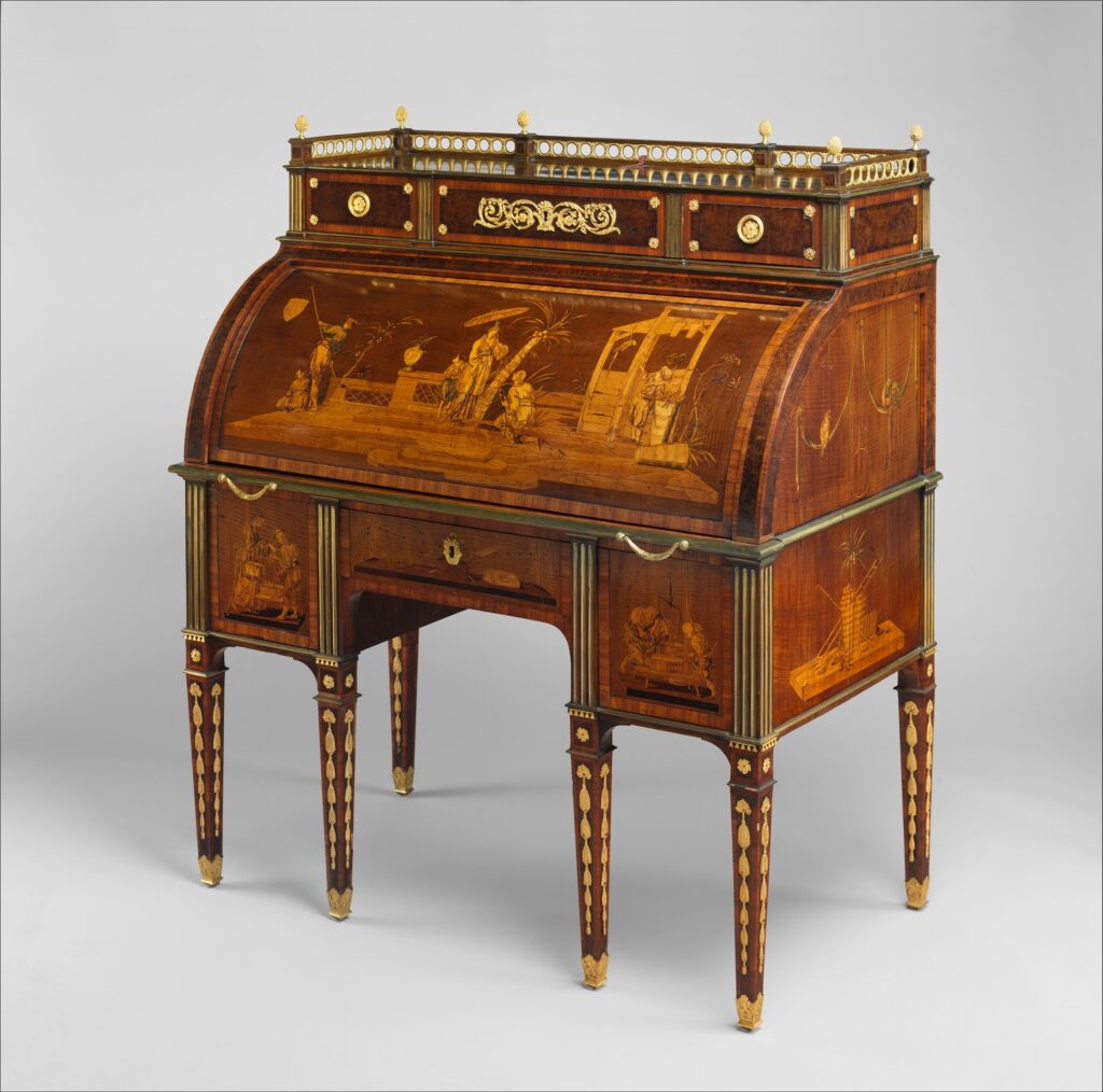 Rolltop desk on six tapering legs, its curved lid inlaid with a marquetry scene of figures in a Chinese-style landscape in pale and golden woods