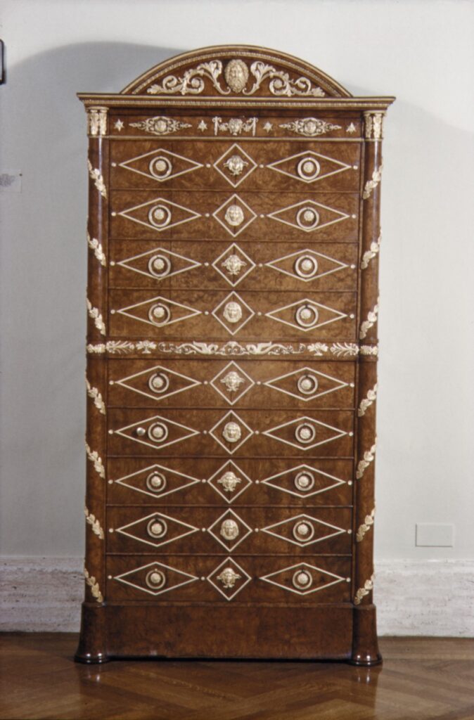 Tall amboyna secretary with an arched top, covered with rows of gilt-bronze mounts laid out like drawer pulls