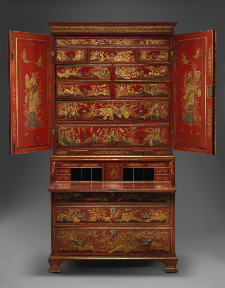Red-and-gold japanned secretary cabinet of about 1735 with both upper doors open to show rows of small decorated drawers, and the writing front lowered to reveal pigeonholes and tiny drawers above three long drawers; a secretary desk shown open