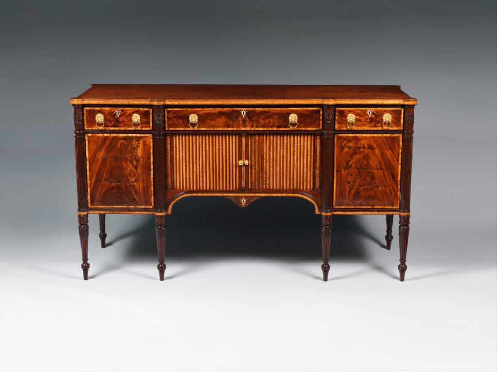 Mahogany sideboard on four slim tapered legs with three drawers across the top, a pair of striped tambour doors at the centre and cupboards at each end