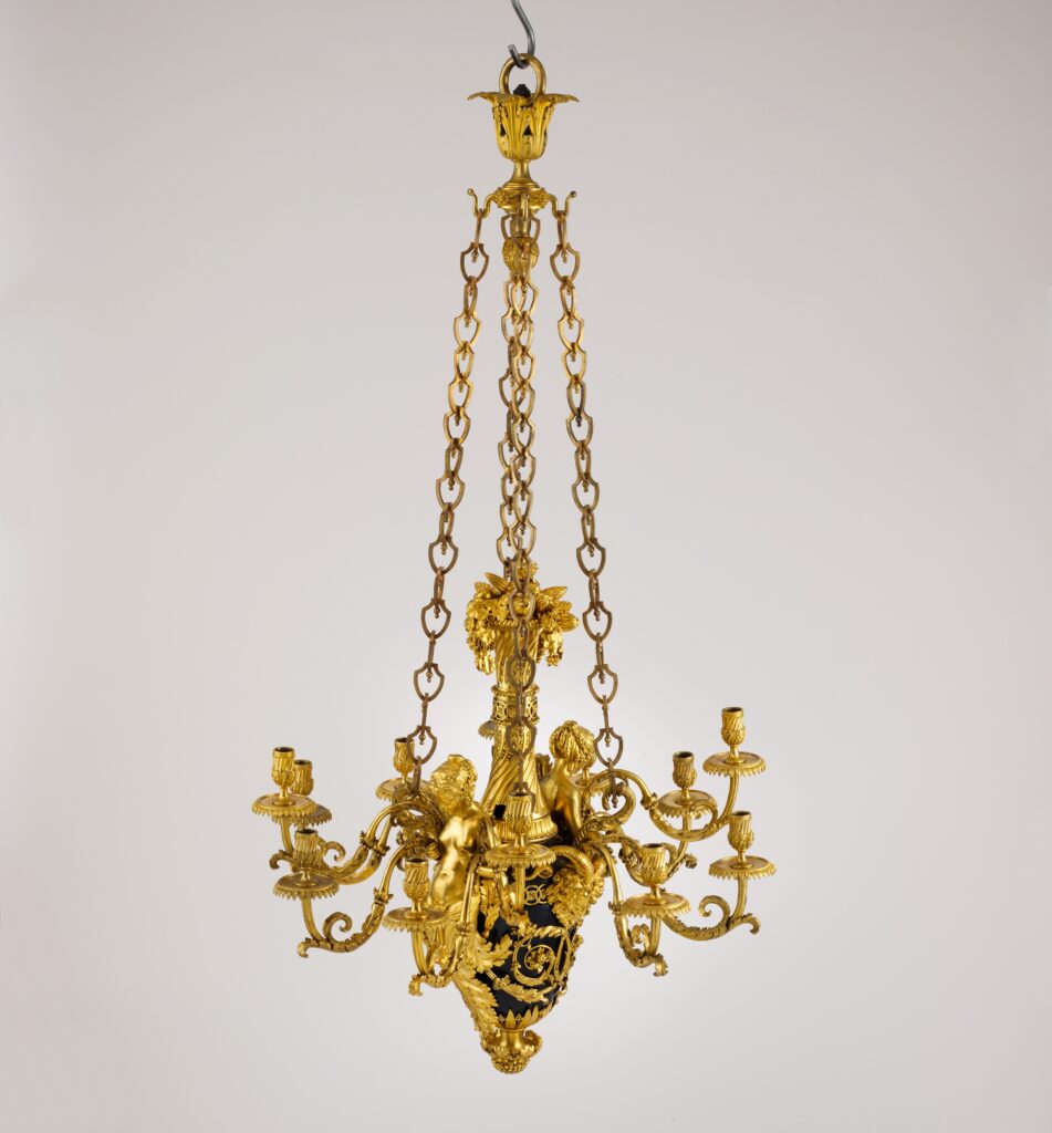 Slender hanging chandelier of gilt bronze with a dark vase-shaped body, small seated figures and curved candle branches, hung from three long chains